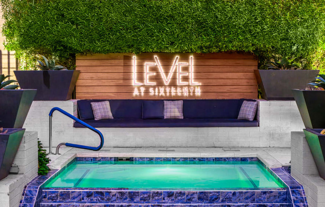 A pool with a blue tiled edge and a wooden sign that says "LEVEL" in front of a green wall.