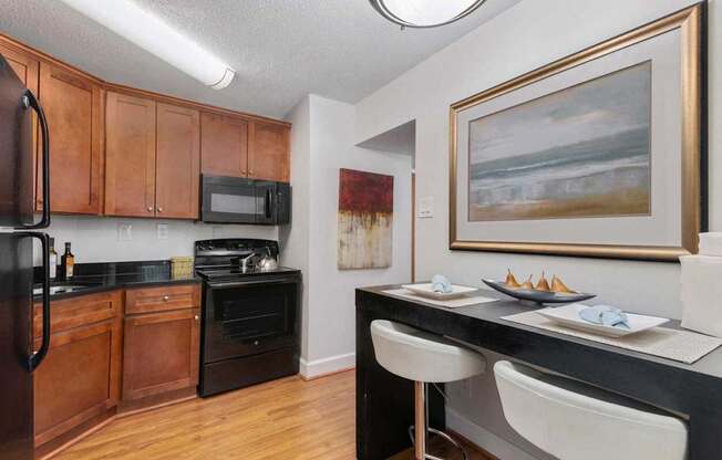 A kitchen with a black counter top and white chairs.