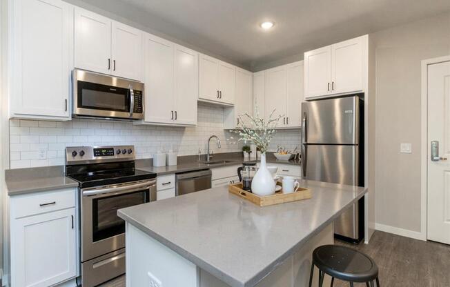 large corner kitchen with white cabinets, stainless steel appliances and island