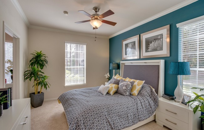 View of Bedroom with Ceiling Fan, Bed, and Nightstands at Raveneaux Apartments