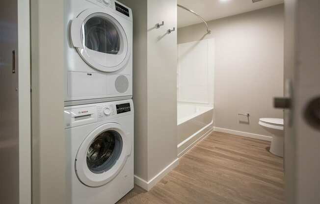 a washer and dryer in a laundry room with a tub and a toilet