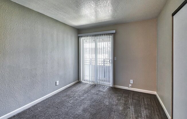 a bedroom with a sliding glass door and a carpeted floor