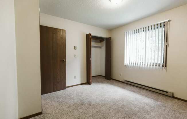 Grand Forks Harrison Apartments. A bedroom with a window and a door to a closet