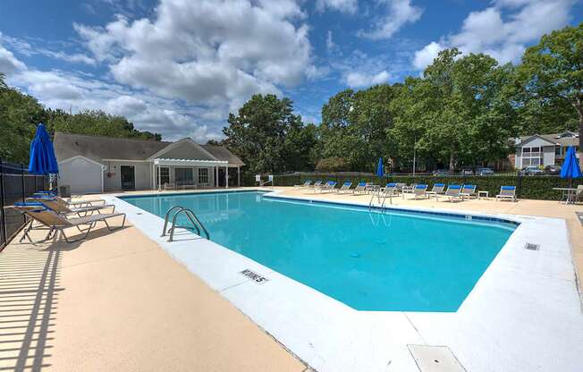 A large outdoor swimming pool with sun loungers and a pavilion in the background.