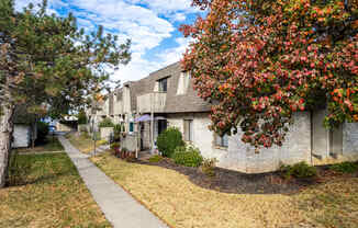 a sidewalk in front of a white brick apartment building
