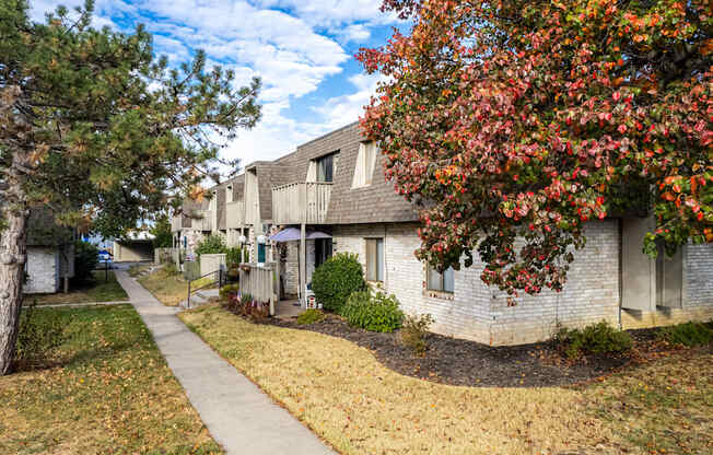 a sidewalk in front of a white brick apartment building