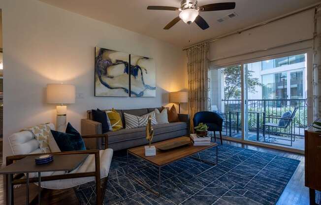 A living room with a grey couch and a painting on the wall.