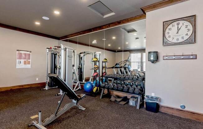 a home gym with weights and a clock on the wall