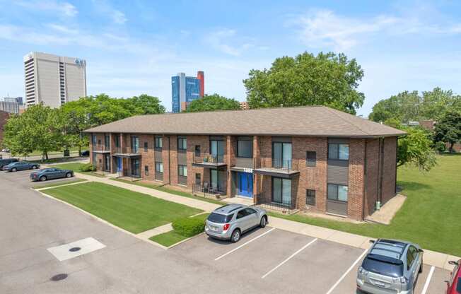 a brick apartment building with a lawn and cars parked in front of it at Lafayette Park Place, Detroit, MI