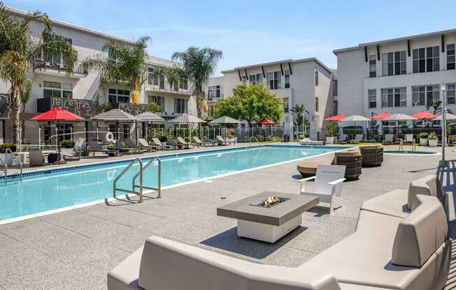 A pool area with a fire pit and lounge chairs.