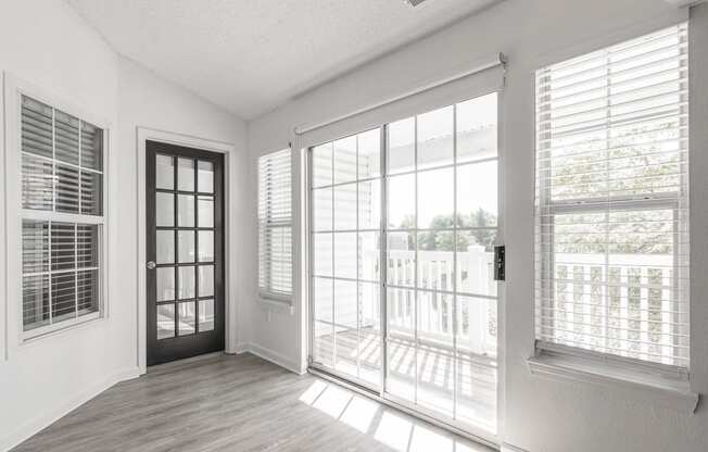 an empty living room with large windows and a door to a balcony