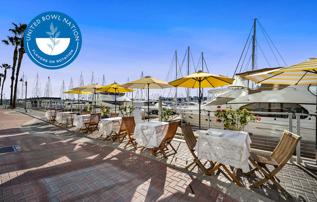 A sunny day at the outdoor seating area of a restaurant with yellow umbrellas at Esprit Marina del Rey, 90292