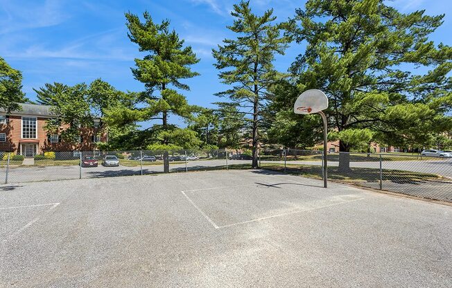 a basketball court with trees and a building in the background