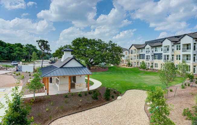 an exterior view of an apartment building with a green lawn and a pathway at Legacy at Cibolo, Texas