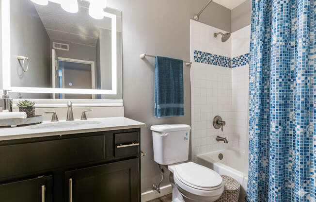 A bathroom with a white toilet, sink, and blue shower curtain.