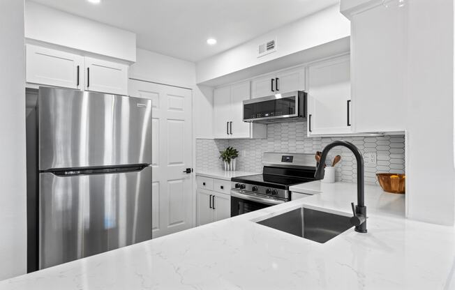 a white kitchen with stainless steel appliances and a sink