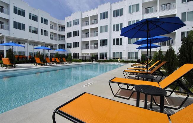 a pool with a bunch of lounge chairs and umbrellas