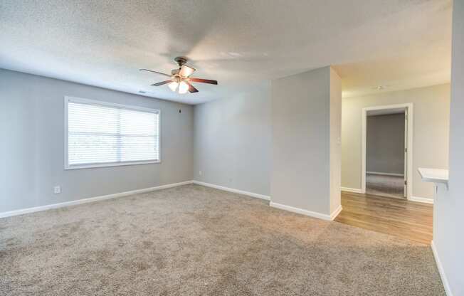 an empty living room with a ceiling fan and a window