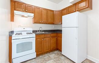 kitchen with oak cabinetry, tile flooring and white appliances at 1400 van buren apartments in washington dc