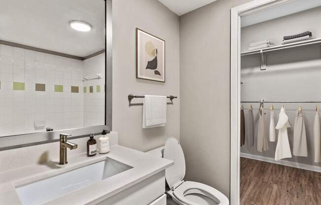 A bathroom with a toilet, sink, and a mirror.