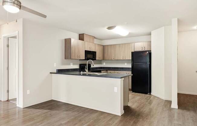 A kitchen with a black fridge and a black microwave.