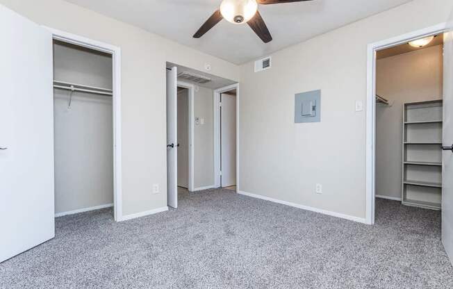 A room with a ceiling fan and a closet with shelves.