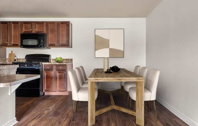 a dining room with a table and chairs and a kitchen in the background