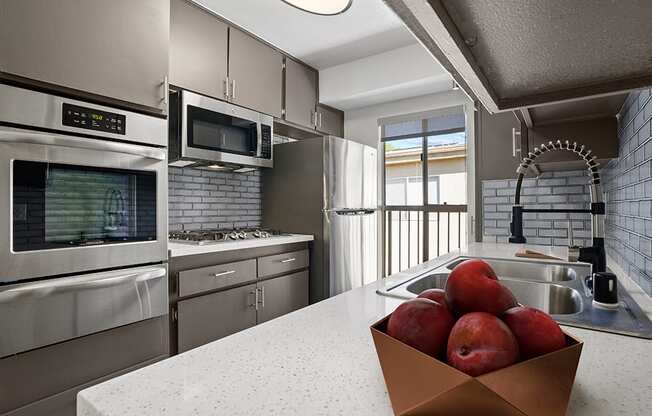 Blue tiled kitchen with stainless steel oven, microwave, fridge, and fixtures.