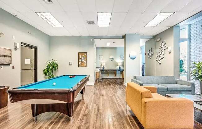 A pool table is in the middle of a room with a couch and a chair.