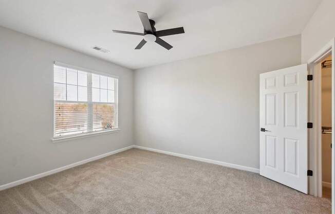 A room with a ceiling fan and a window with blinds.