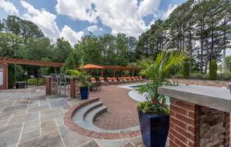 a patio with brick pillars and a seating area with potted plants