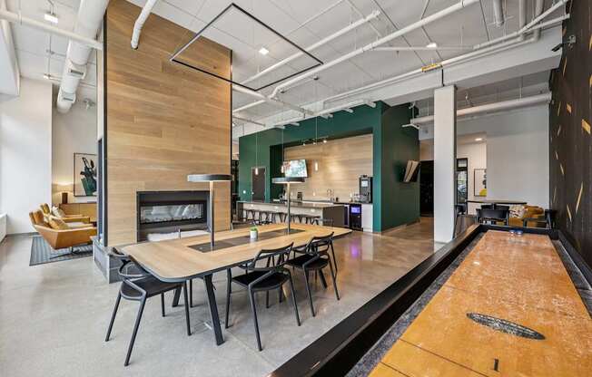 A room with a long table and chairs, a fireplace, and a bowling alley.