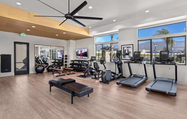 a gym with a lot of exercise equipment and windowsat Westbury Apartments, Rancho Cucamonga, California