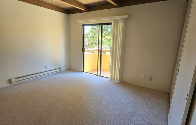 an empty living room with a sliding glass door to a patio