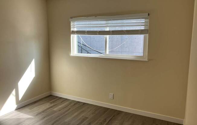 A room with a window and wooden flooring.