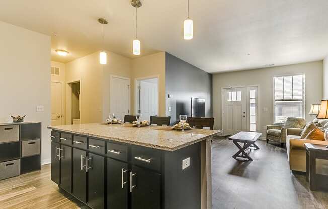 a kitchen with an island and a living room in the background