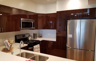 A modern kitchen with dark wood cabinets and stainless steel appliances at Woodley Sara Apartment, Van Nuys, 91406