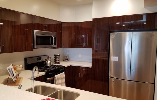 A modern kitchen with dark wood cabinets and stainless steel appliances at Woodley Sara Apartment, Van Nuys, 91406