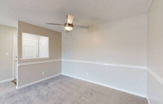 an empty living room with a ceiling fan and a window
