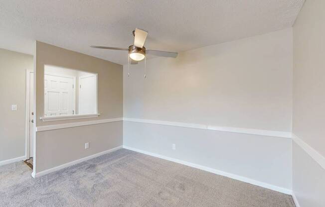 an empty living room with a ceiling fan and a window