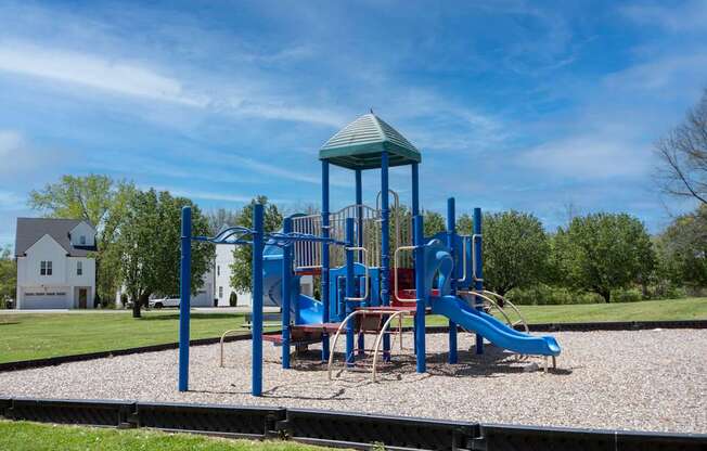 A playground with a blue slide and a green roofed structure.
