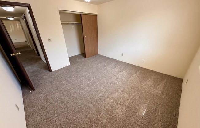 A carpeted room with a door and a mirror on the wall.