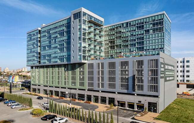 A modern glass and concrete building with cars parked in front.