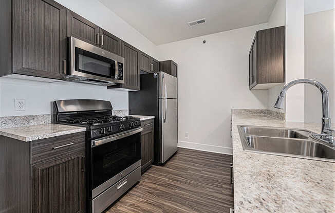 A kitchen with dark wood cabinets and stainless steel appliances at Copper Creek Apartment Homes, Maize