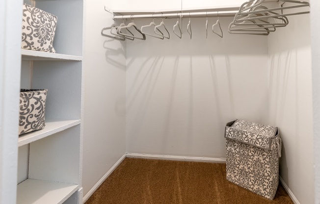 a walk in closet with white walls and shelves and a bag on the floor