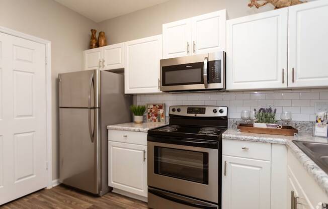 A kitchen with a stainless steel refrigerator, oven, and microwave.
