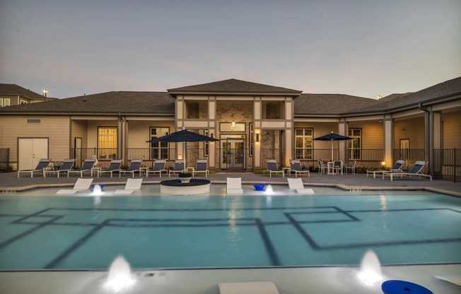 a large pool with chairs and umbrellas at dusk