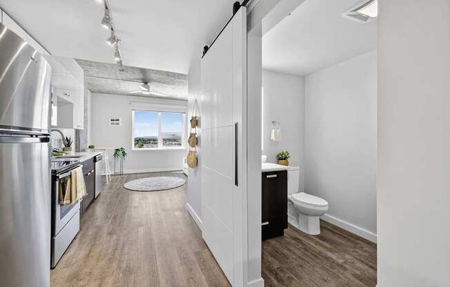 A kitchen with a refrigerator, toilet and sink.