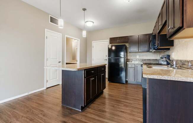 A kitchen with dark wood cabinets and a black refrigerator.