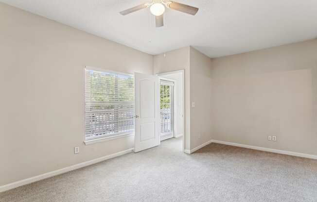 an empty living room with a ceiling fan and a window